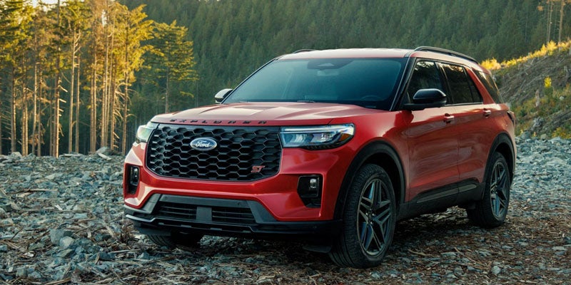 Red Ford Explorer SUV parked on a rocky forest path